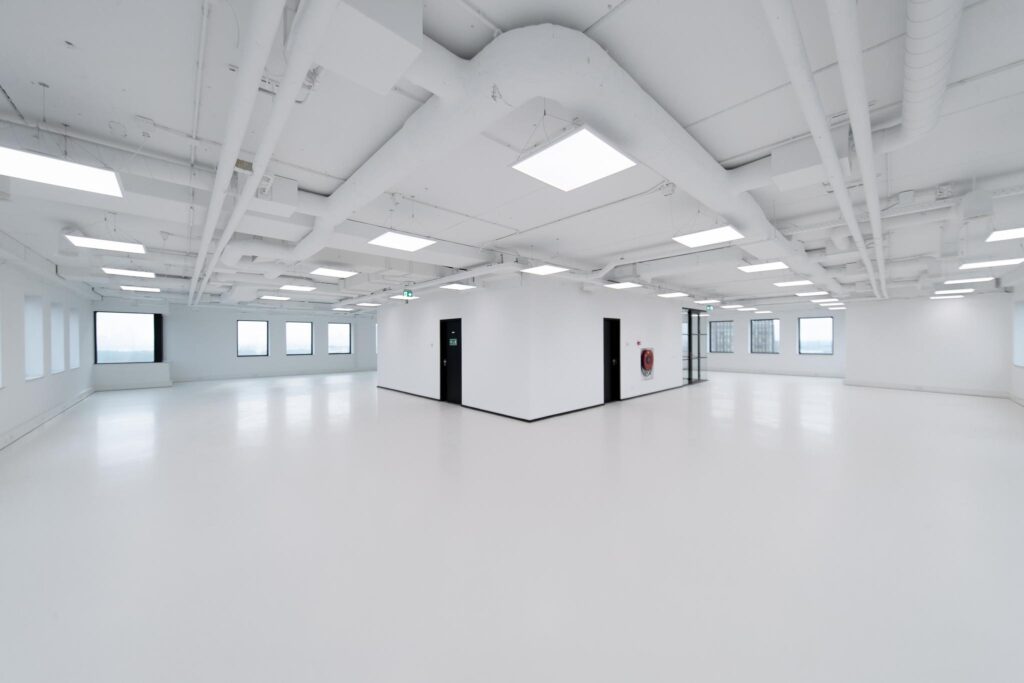 Licht en modern leeg kantoorpand in Rivium Quadrant met witte vloeren, plafonds en zichtbare leidingen.